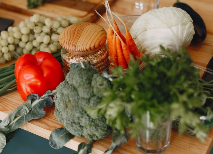 A vibrant display of fresh vegetables and fruits on a wooden board, including bell pepper, cabbage, and more.
