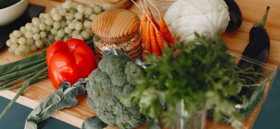 A vibrant display of fresh vegetables and fruits on a wooden board, including bell pepper, cabbage, and more.