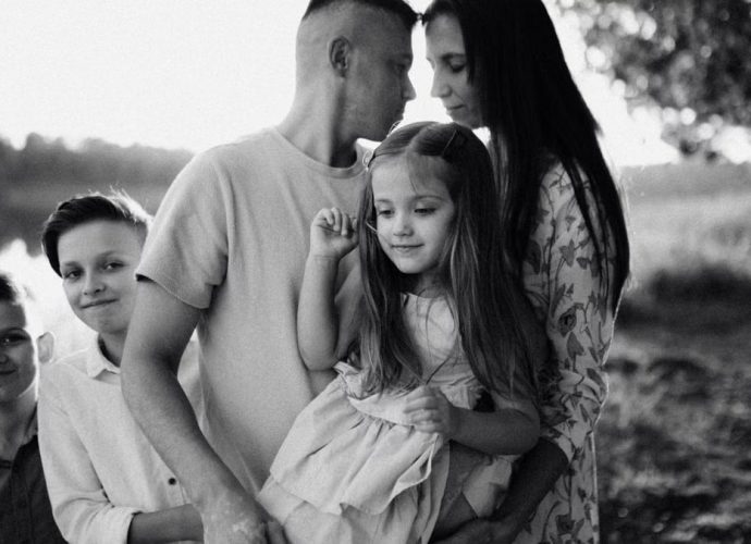 A serene black and white portrait of a family standing by a lake.