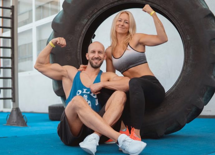 Energetic couple showing strength and fitness at the gym with a large tire.
